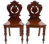 A pair of Victorian carved mahogany hall chairs:,