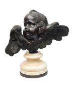 A bronzed head of a winged cherub: looking skyward with outstretched wings,