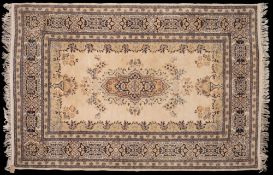 A Kashmiri rug:, the ivory field with a central indigo shaped medallion and floral foliate designs,