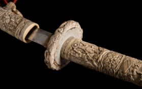 A Japanese ivory wakizashi: finely carved overall with numerous figures in interiors and landscapes,