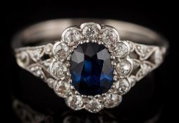 A sapphire and diamond oval cluster ring: the oval sapphire approximately 6mm long x 4.8mm wide x 2.