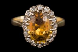 A chrysoberyl and diamond oval cluster ring: with central oval yellow chrysoberyl claw-set within a