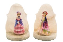 A pair of Royal Doulton bookends: the alabaster mounts set with two figures of girls wearing
