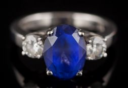 An 18ct white gold, tanzanite and diamond three-stone ring: the oval tanzanite 10.3mm long x 7.
