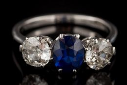 A sapphire and diamond three-stone ring: with central oval sapphire between round old brilliant-cut