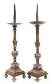 A matched pair of bronze pricket candlesticks: of traditional design with circular drip trays on a