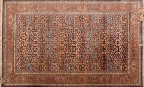 A Qum rug:, the indigo field with all over palmette and flowering stems in ogee surrounds,