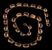 A graduated topaz riviere necklace: in cut-down collet settings,
