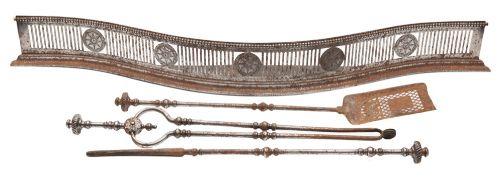 A George III pierced steel serpentine-fronted fender and a set of fire irons: the fender with