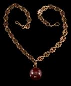 A late 19th century watch chain: with attached red amber type, 54gms weight of chain.