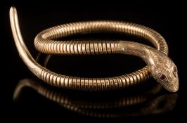 A 9ct gold 'snake' bangle: with hall marked head and tail and pink gem-set eyes.