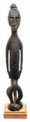 A Papua New Guinea (Sepik river area) carved ebony tribal figure: stained black with inset shell