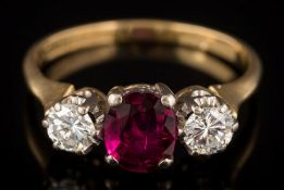 An 18ct gold ruby and diamond three-stone ring: with central oval ruby 6.9mm x 5.