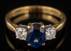 An 18ct gold, sapphire and diamond three-stone ring: with central oval sapphire approximately 7.