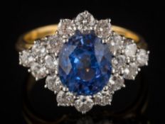 An 18ct gold, sapphire and diamond oval cluster ring: with central oval sapphire approximately 9.