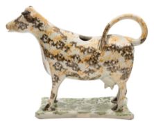 A Staffordshire creamware cow creamer: painted in marbled grey, ochre and green glazes,