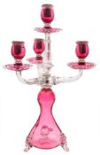 A cranberry and clear glass candelabra: the bulbous waisted base on three feet supporting a central