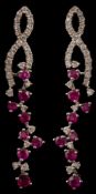 A pair of modern ruby and diamond pendant earrings: with stylised openwork ribbons suspending