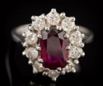 An 18ct white gold, ruby and diamond oval cluster ring: with central oval ruby approximately 9.