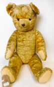 A large pale plush Teddy bear: with rounded wide-apart ears, glass eyes,