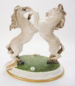A Capo di Monte porcelain equestrian group: of two rearing horses, on an oval base, 33cm. high.
