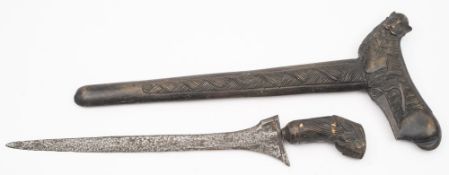 A Malayan Kris:, of typical form with lion's mask carved grip and carved wooden scabbard,