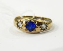 Gold coloured three-stone ring with central circular blue stone flanked by a pair of white-coloured