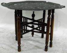 Eastern octagonal brass tray with overall foliate engraving, on a folding stand,