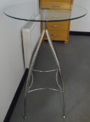 Modern circular high glass pedestal table on four metal supports united by stretchers,
