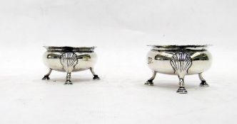 Pair of early 20th century silver salts, circular with shell-shaped legs and spade feet,