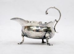 George II silver sauceboat of squat form with cut card border, on three scroll paw feet,