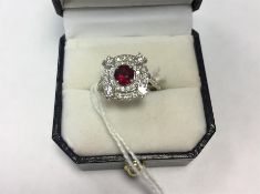 18K white gold, ruby and diamond cluster ring set centre circular facet-cut Burmese ruby with
