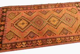 Large cotton kelim, having central row of four hooked lozenge medallions, on madder red ground, with