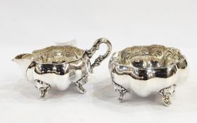 German silver-coloured metal sugar bowl and matching cream jug, each raised on four scroll tab