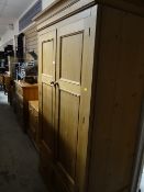 A pine two-door wardrobe with two-drawer base