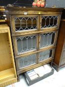 A vintage oak three sectioned leaded glass door bookcase on raised barley-twist feet