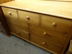 A narrow pine low chest of drawers with three short above four other drawers