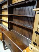 A vintage dark stained oak dresser on raised legs with two-door cupboard base & rack