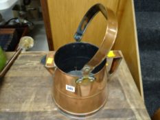 A polished copper pouring jug with carry handle
