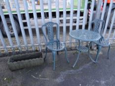 A painted green metal three-piece patio table & chairs set together with a garden trough (outside)