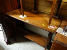 An Edwardian oak console-style table with lower shelf & on castors