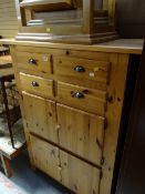 A tall honey pine chest comprising four small drawers above a pair of two-door cupboards together