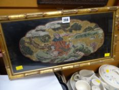 A framed gilt & painted Oriental panel depicting a seated male under a tree