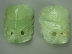 TWO JADITE CARVED MASK BELT BUCKLES, 6.5 x 5 cms