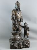 A LARGE JAPANESE BRONZE FIGURE of a fisherman with boy and basket, hollow cast, raised on a rocky