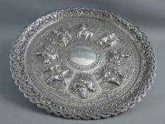 A BURMESE WHITE METAL FIGURAL EMBOSSED CIRCULAR TRAY, the edge decorated with entwined snakes and