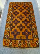 A BALUCHI WOOLLEN RUG, rust ground with cross patterned central panel and repeating running