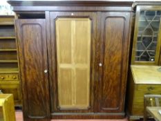 A VICTORIAN FIGURED MAHOGANY TRIPLE WARDROBE with stepped cornice over three panelled doors (