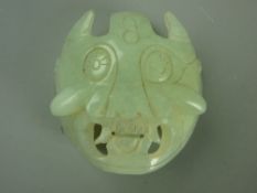A CARVED JADE BELT MASK, 5.5 cms across
