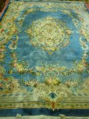 A LARGE WASHED WOOLLEN CHINESE CARPET, blue ground with central floral motif, swag decoration and